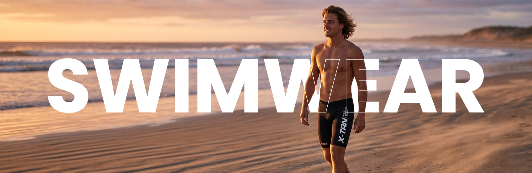 Male athlete walking on beach wearing X-TRN swimwear for performance and active lifestyle